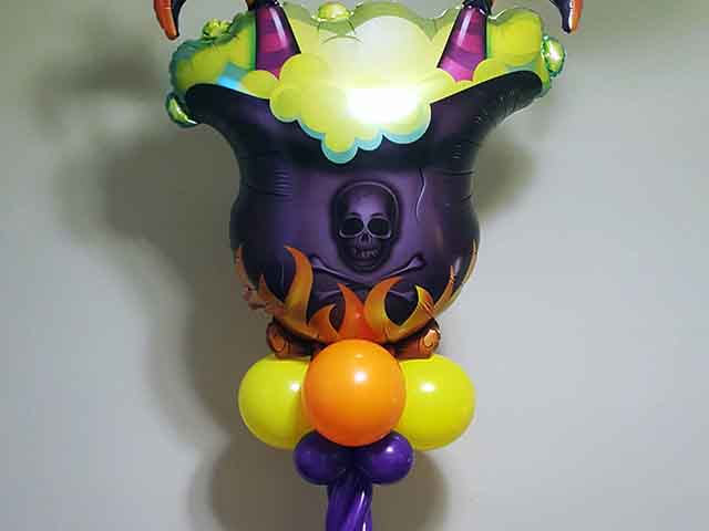 Halloween themed column with bat and skeleton printed balloons at the bottom with a witch's brew at the top