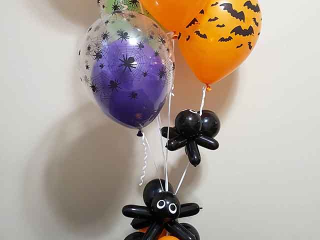 Halloween themed bouquet with spider and bat printed balloons as well as balloon spiders crawling up the bouquet