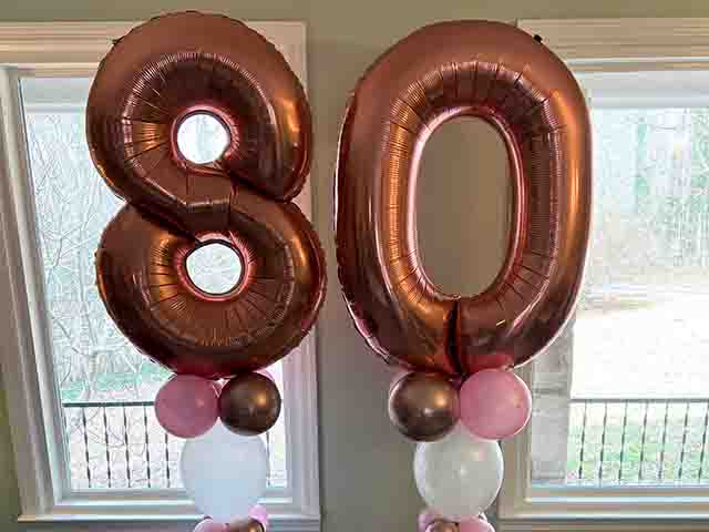 Two slim balloon columns with the numbers 8 and 0